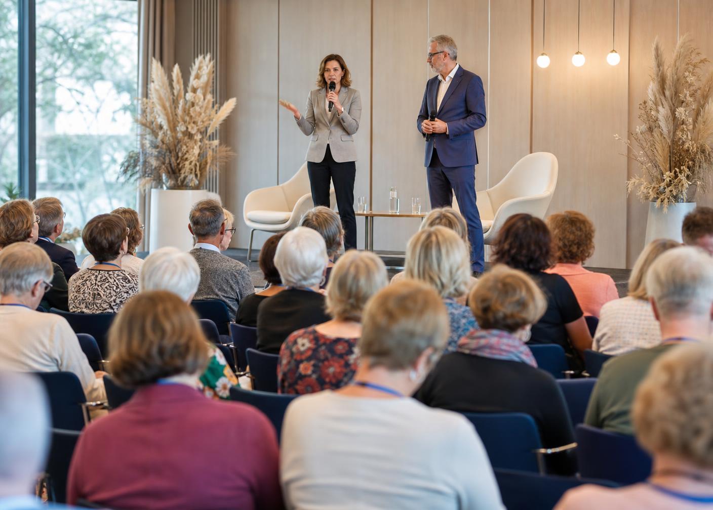 Zwei Referenten auf der Bühne des Pflegekongresses vor einem aufmerksamen Publikum